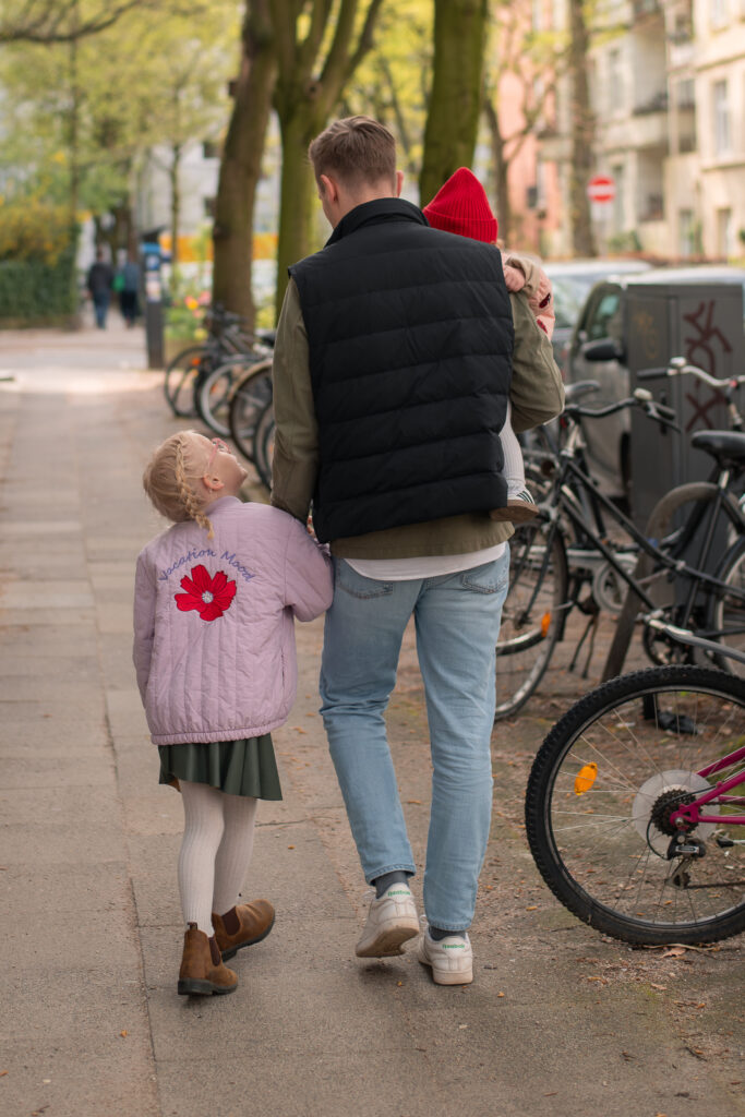 Natürliches Familienfoto mit einem Vater und seinen zwei Töchtern beim Spaziergang.